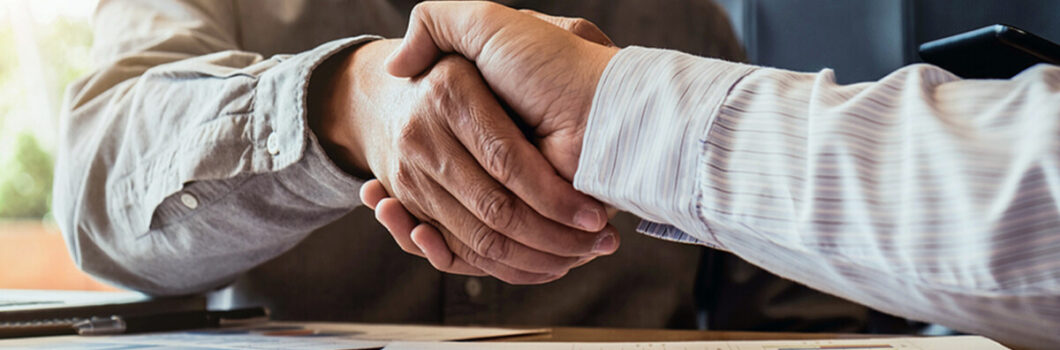 two businesspeople shake hands after making a deal.