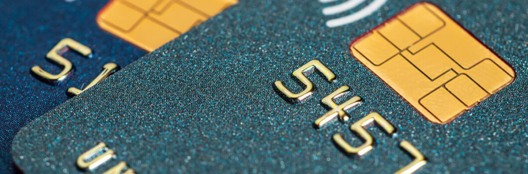 a close-up of a dark green credit card with chip sitting on top of a dark blue credit card with chip.