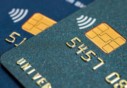 a close-up of a dark green credit card with chip sitting on top of a dark blue credit card with chip.