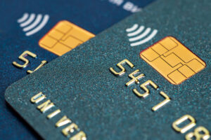 a close-up of a dark green credit card with chip sitting on top of a dark blue credit card with chip.