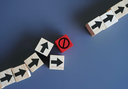 a line of blocks with arrows painted on them are interrupted by a block with the universal no sign painted on it.