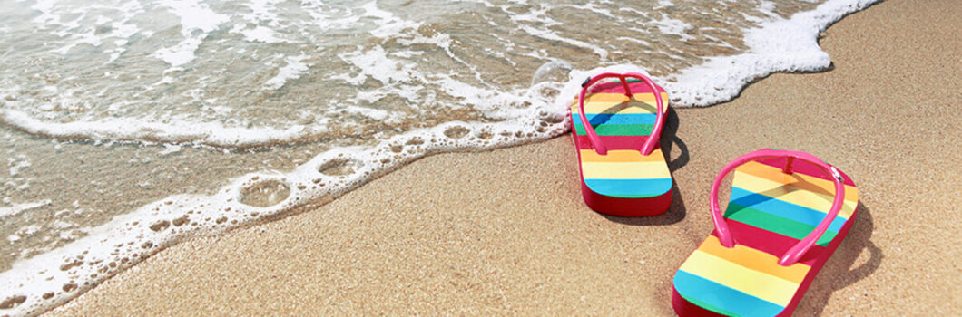 a pair of rainbow sandals on a sandy beach.
