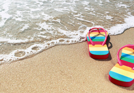 a pair of rainbow sandals on a sandy beach.