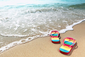 a pair of rainbow sandals on a sandy beach.
