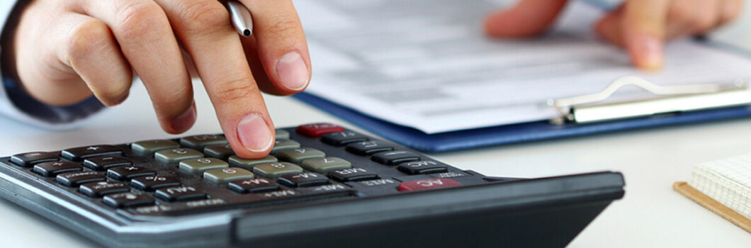 an auditor looks at forms and works on a calculator.
