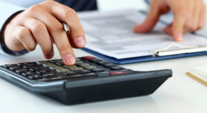an auditor looks at forms and works on a calculator.