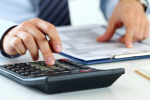 an auditor looks at forms and works on a calculator.