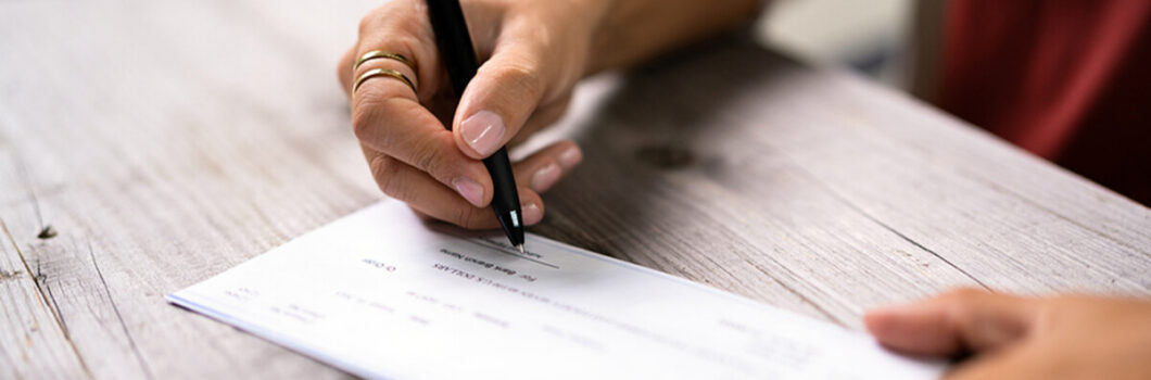 a woman writes on a payroll check.
