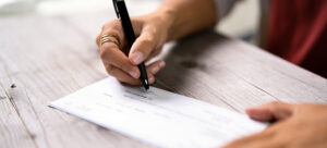 a woman writes on a payroll check.