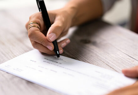 a woman writes on a payroll check.