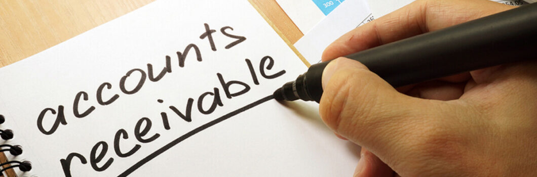 a person writes the words accounts receivable on a notepad.