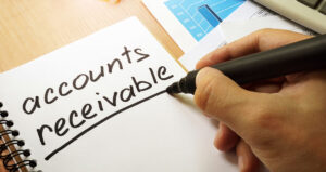 a person writes the words accounts receivable on a notepad.