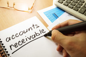 a person writes the words accounts receivable on a notepad.