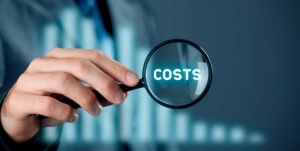 a businessman puts a magnifying glass over the word costs.