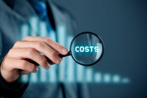 a businessman puts a magnifying glass over the word costs.