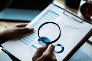 a person holds a magnifying glass to a financial report.